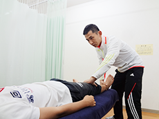 真剣に下肢の手技を行う院長