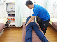 うつ伏せの患者の腰部を押さえるようす