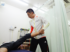 若い男性の下肢を広げ施術を行うようす