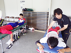競技場の控室で選手に施術を行うようす