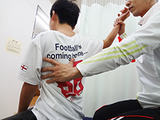 若い男性の腕を持ち肩甲骨周辺を押さえ施術するようす